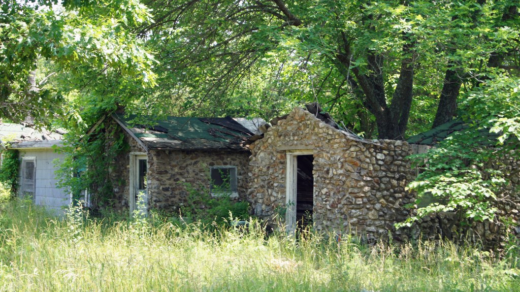 Spring Valley Court was established early, about 1929, with four rock cabins and the foreground rock shower house. The remodeled house was the store and cafe. Below the house is a spring where travelers would water their horses and, later, their auto. (MO1)